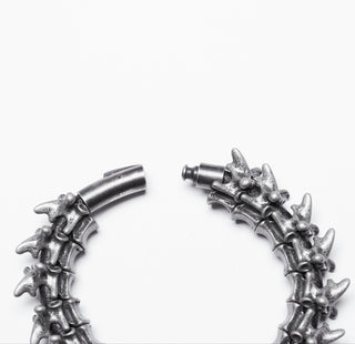 Open clasp view of silver vertebrae-style bracelet on white background