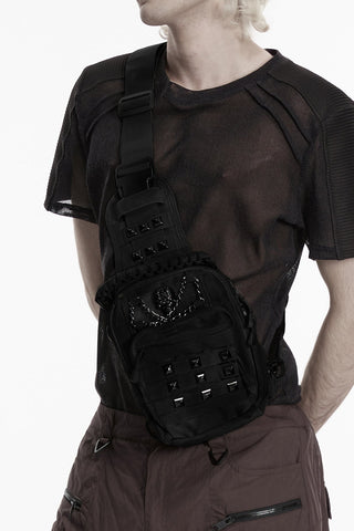 Model wearing black cyber goth sling bag with skull chain detail and studded front pocket