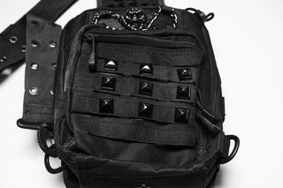 Close-up of studded front pocket and utility strap details on black sling bag