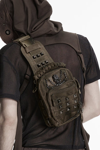 Back view of model wearing brown distressed utility sling bag with skull chain hardware and studded details