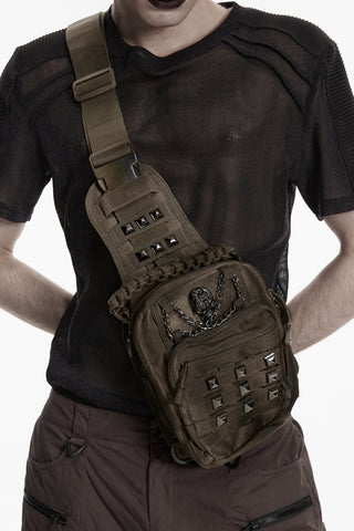 Model wearing brown distressed cyber goth sling bag with skull chain detail and studded front pocket