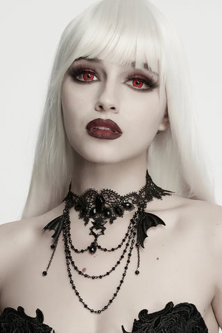 Model wearing a black lace choker necklace with bat-wing details and dangling chains.