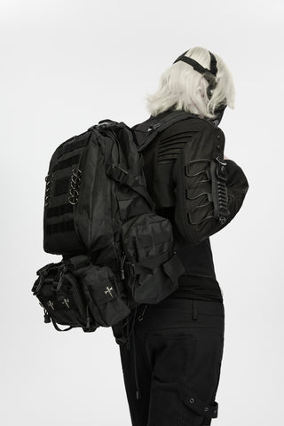 Rear view of a person wearing a black tactical backpack with multiple straps and attached pouches.