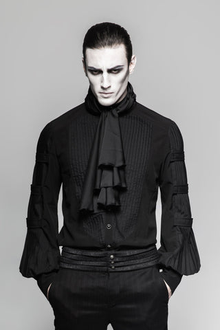 Man wearing a black Gothic shirt with pleated sleeves, layered cravat, and double belt trousers, hands in pockets, grey background