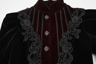 Close-up of burgundy velvet front panel with ornate black floral embroidery and rose-design buttons