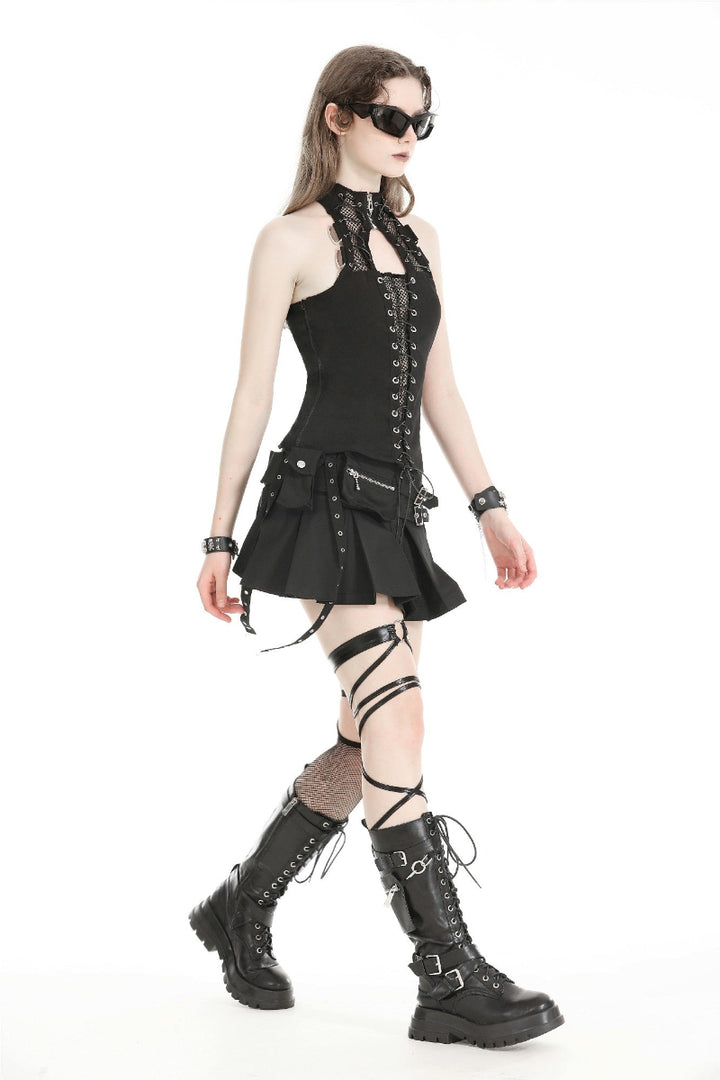 Model walking in a black techwear pleated mini skirt with two utility pockets, buckled straps, and combat boots