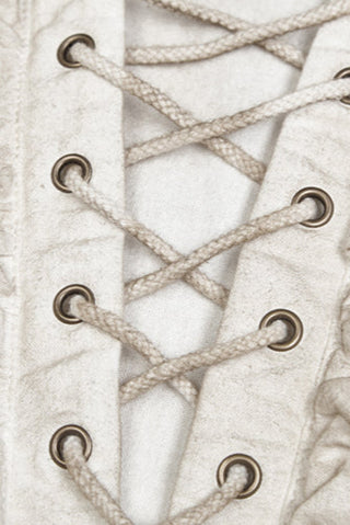 Close-up of chest lacing and metal eyelets on distressed white pirate-style shirt