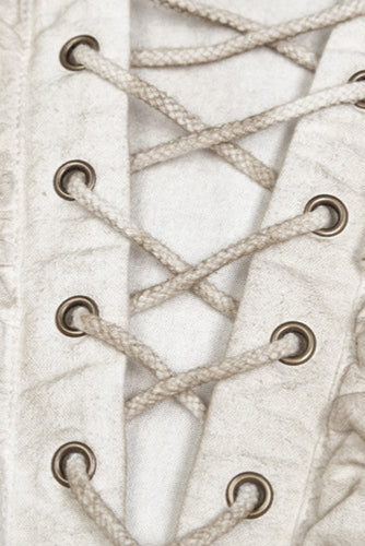 Close-up of chest lacing and metal eyelets on distressed white pirate-style shirt
